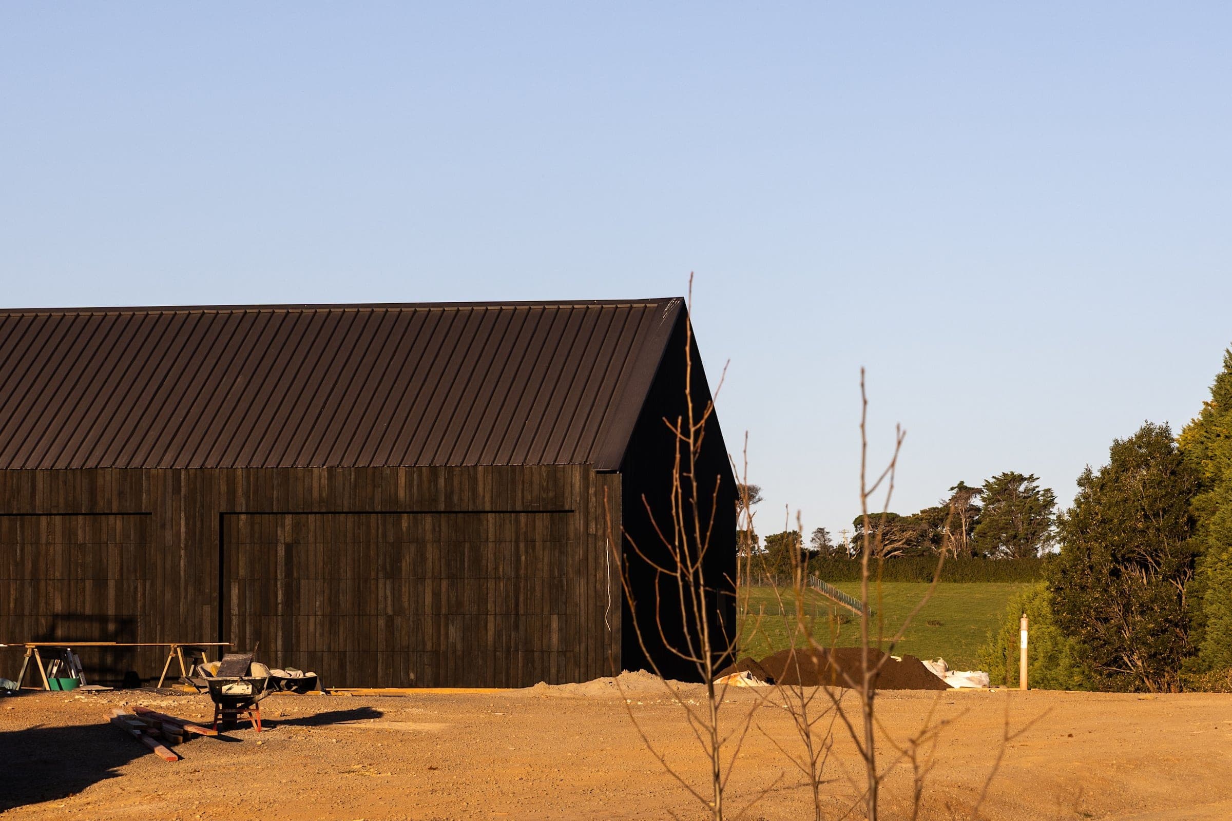 A charred-timber outbuilding on freshly graded ground at Halls Road