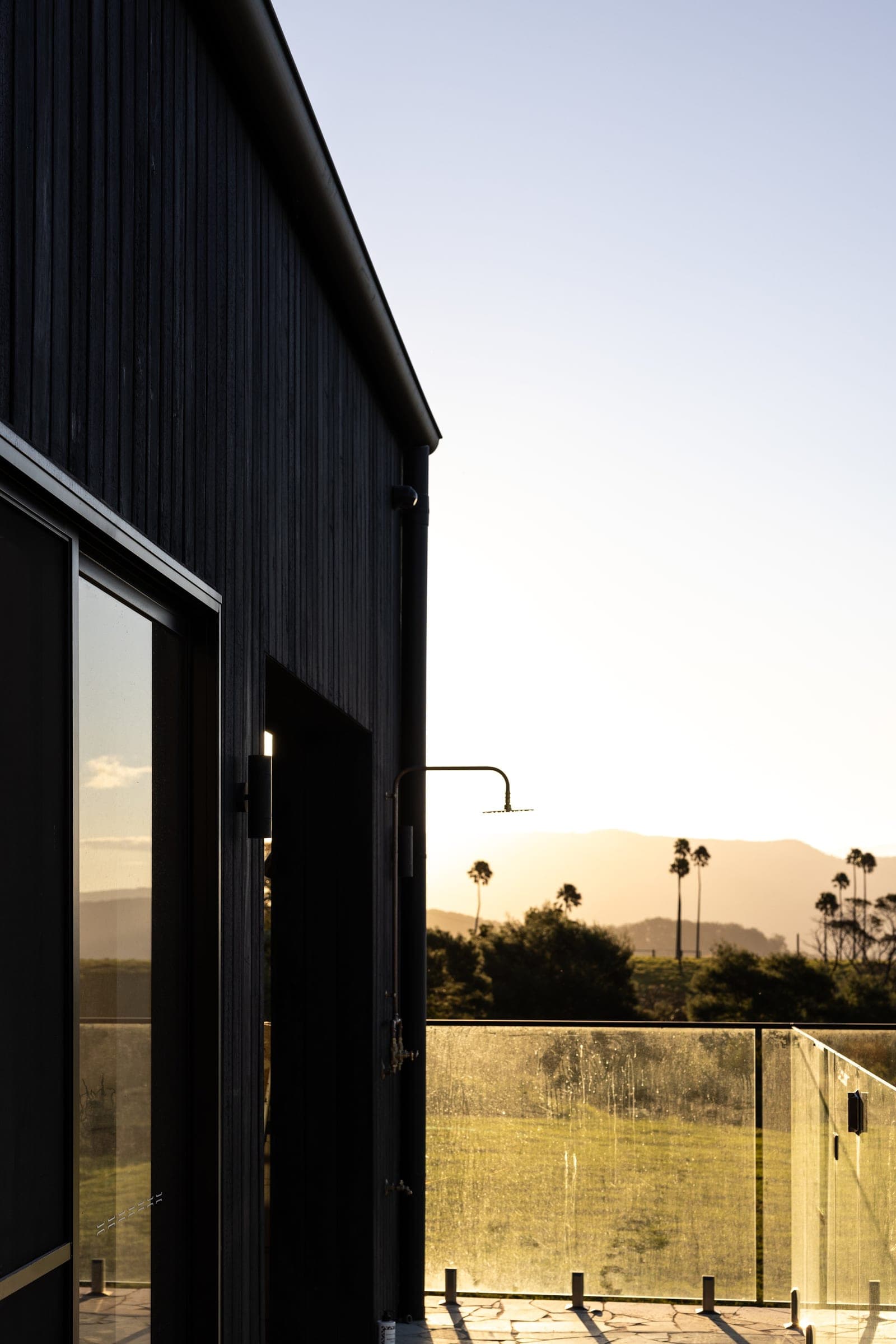 Charred cladding and a glass balustrade looking out over the Jerrara hills