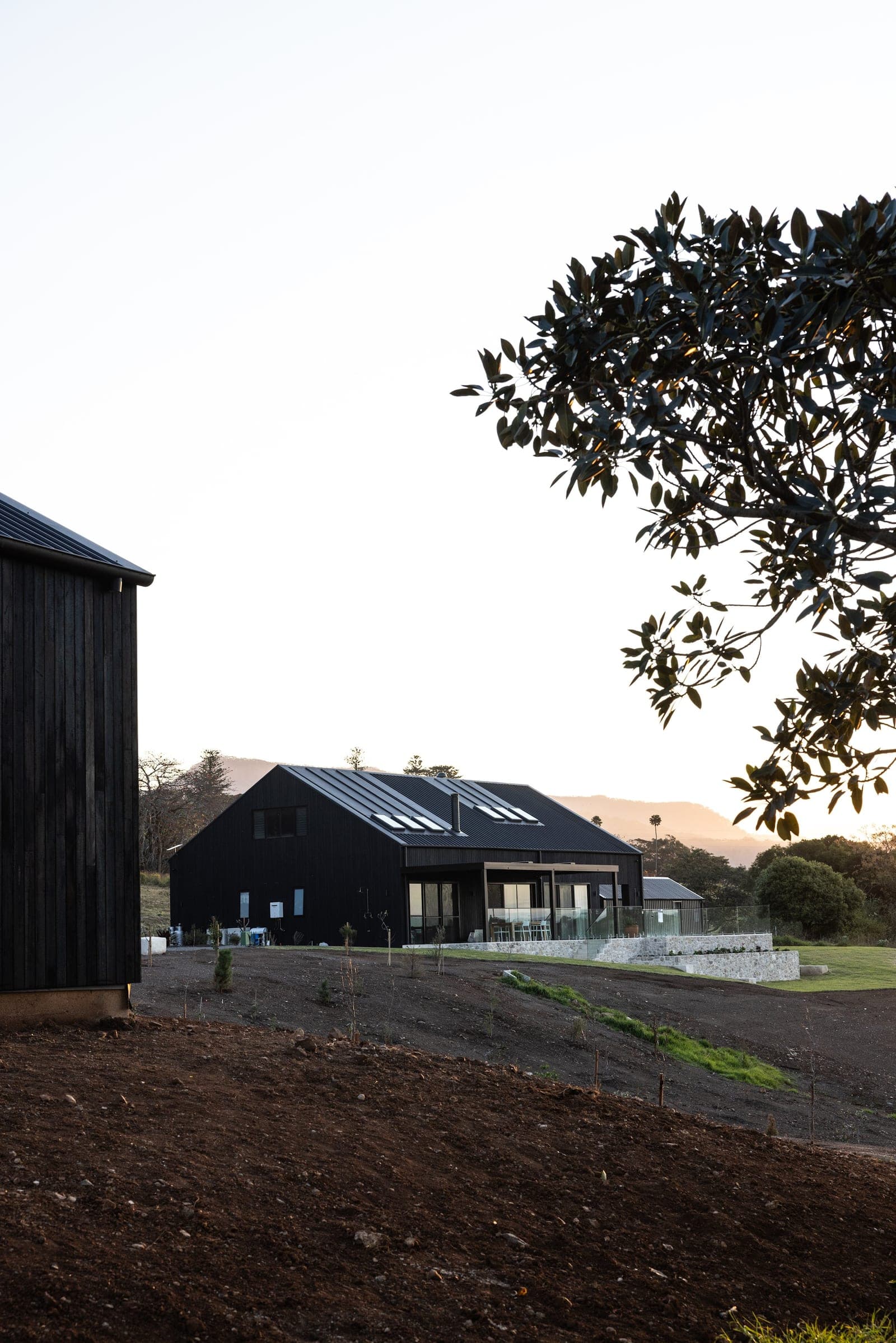 Halls Road seen across the farm from beside a charred-timber outbuilding