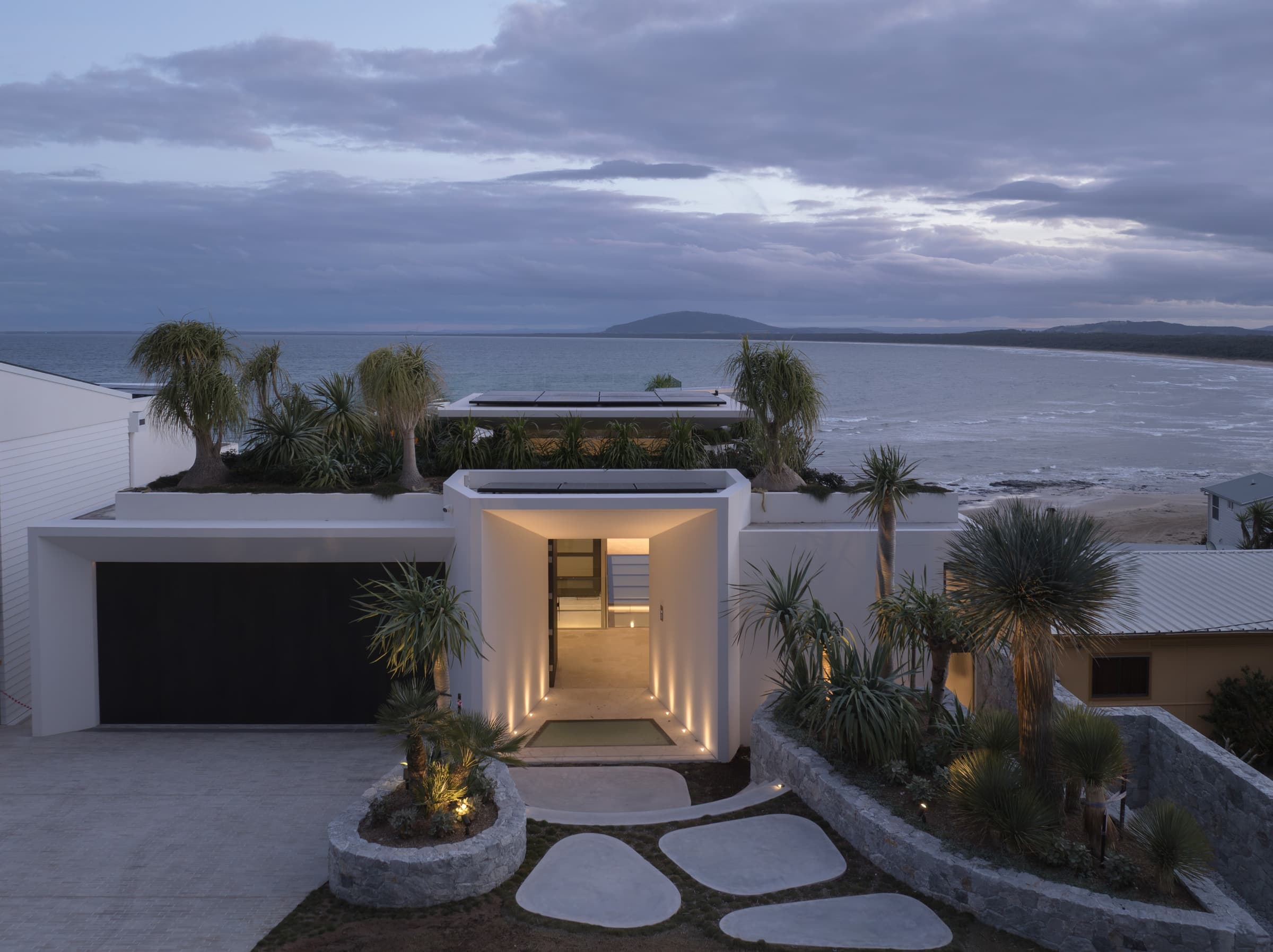 Stafford at dusk: the three-storey home stepping down its rock-shelf site above Seven Mile Beach, Gerroa